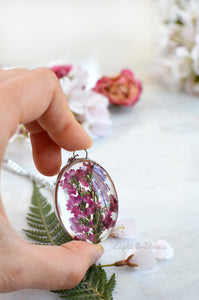 A pendant featuring pressed heather blossoms preserved in glass.