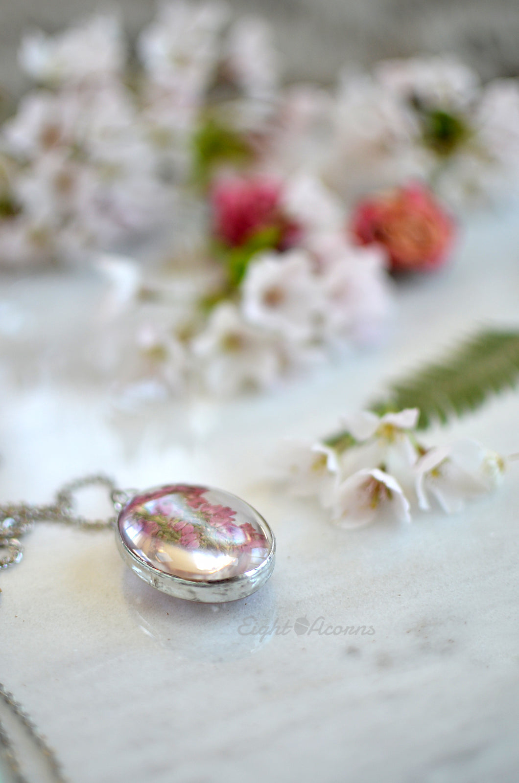 A pendant featuring pressed heather blossoms preserved in glass.