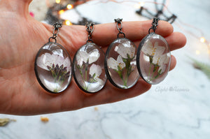 A pendant featuring cherry blossoms preserved in glass (stained glass technique, black patina).